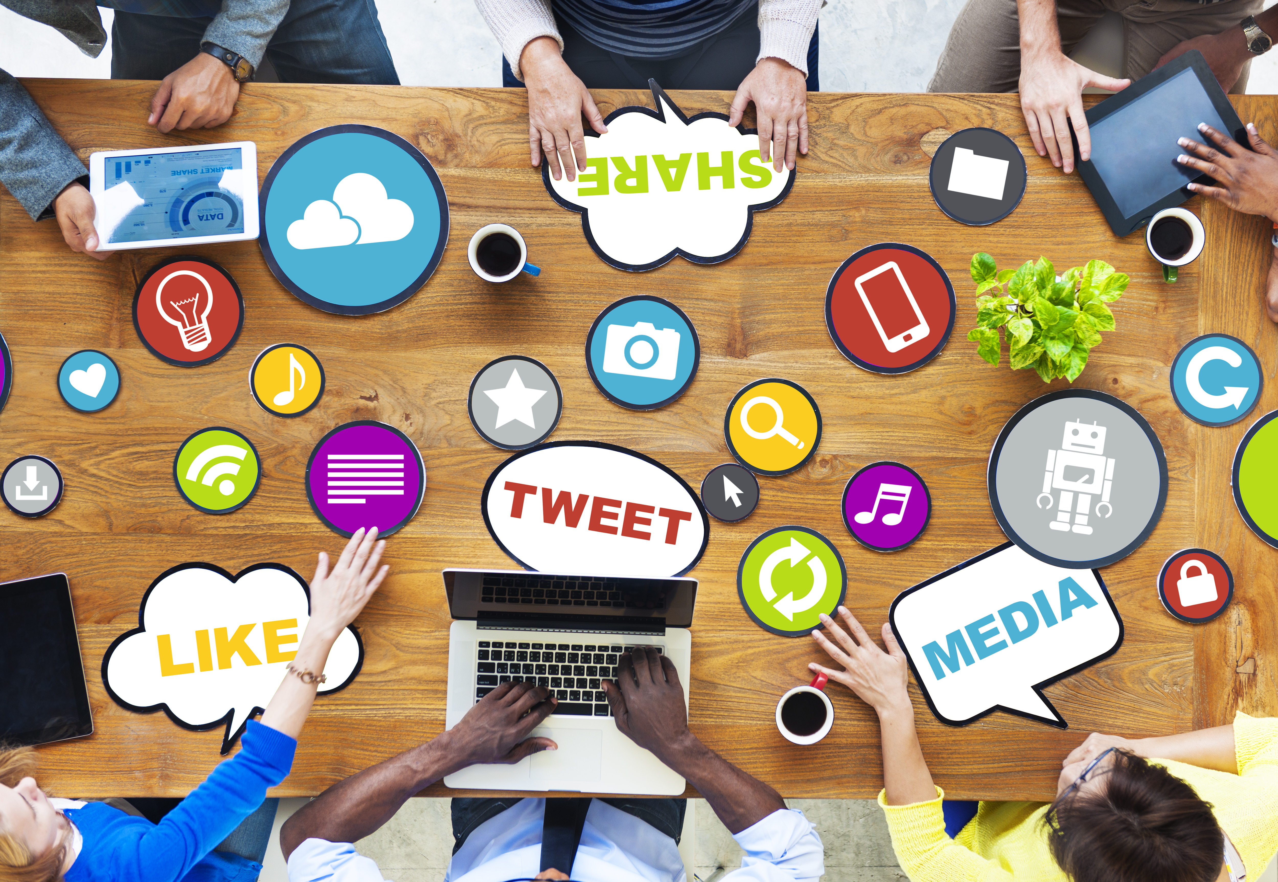 multiple people at table having meeting with social media icons on table